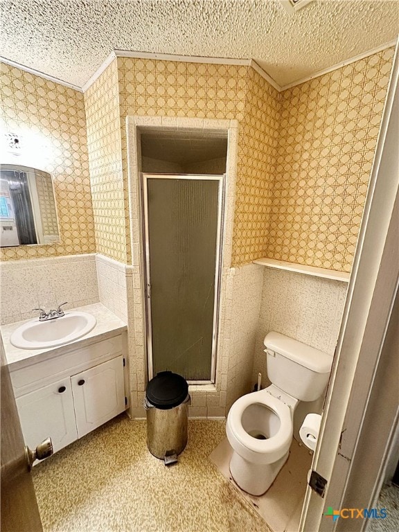 bathroom featuring vanity, a textured ceiling, toilet, and a shower with door