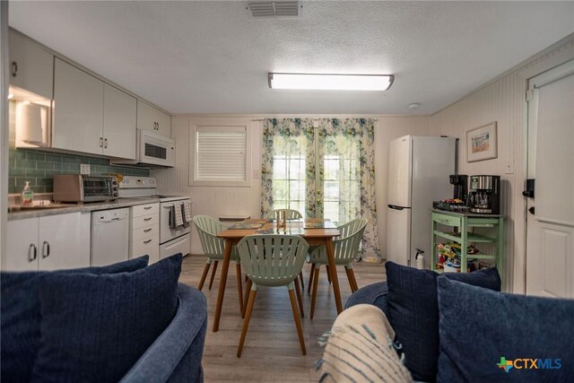 819 S Magnolia St, Rockport, TX 78382 - kitchen with white appliances, open floor plan, light wood-type flooring, decorative backsplash, and white cabinets