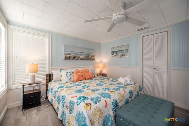 819 S Magnolia St, Rockport, TX 78382 - bedroom featuring wood finished floors, a closet, wainscoting, and a ceiling fan