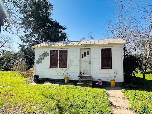 bungalow-style house with entry steps, metal roof, a front lawn, and a standing seam roof