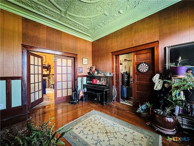 living area featuring french doors, wood walls, wood finished floors, and an ornate ceiling