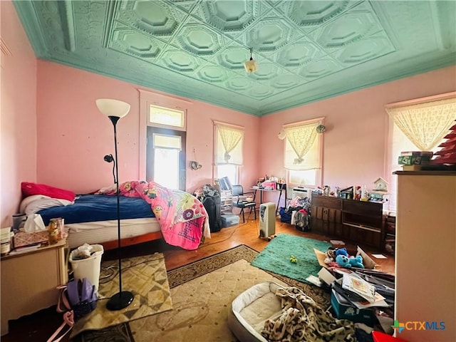 bedroom featuring an ornate ceiling, ornamental molding, and wood finished floors