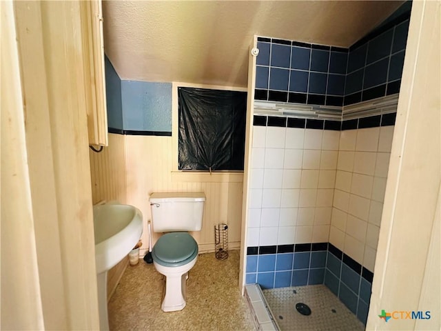 full bathroom with toilet, a wainscoted wall, and a shower stall