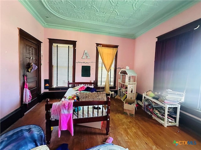 bedroom with an ornate ceiling, ornamental molding, and wood finished floors