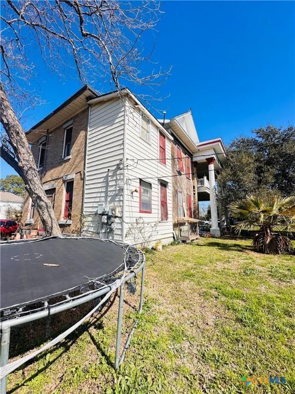 view of side of property featuring a yard and a trampoline