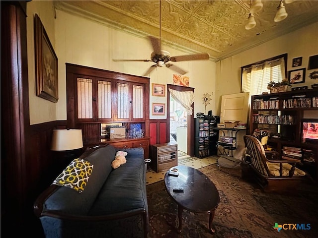 living area featuring crown molding, an ornate ceiling, and a ceiling fan