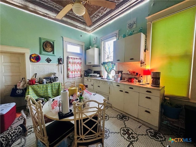 kitchen featuring an ornate ceiling, light countertops, white cabinetry, ceiling fan, and a sink