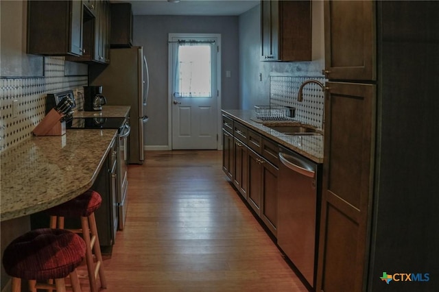 22631 John Rolfe Ln, Katy, TX 77449 - kitchen featuring appliances with stainless steel finishes, light wood finished floors, tasteful backsplash, and light stone counters