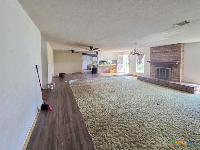 403 Schell Rd, Victoria, TX 77904 - unfurnished living room with a fireplace, a textured ceiling, wood finished floors, a chandelier, and ceiling fan