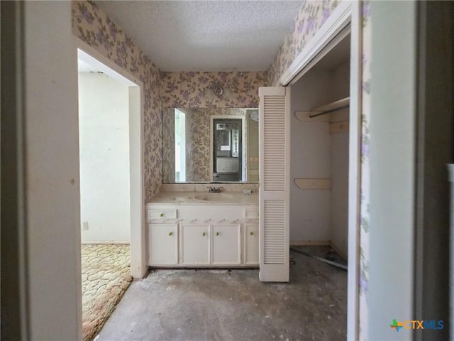 403 Schell Rd, Victoria, TX 77904 - bathroom with vanity, a closet, a textured ceiling, and wallpapered walls