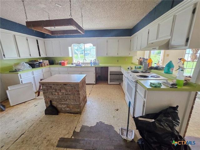 403 Schell Rd, Victoria, TX 77904 - kitchen with white range with electric stovetop, under cabinet range hood, light countertops, white cabinetry, and plenty of natural light