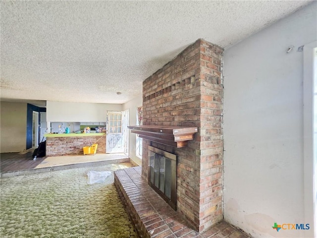 403 Schell Rd, Victoria, TX 77904 - unfurnished living room with a textured ceiling, a brick fireplace, and carpet floors
