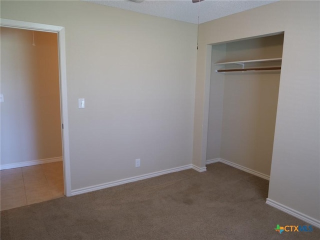 unfurnished bedroom with carpet floors, tile patterned flooring, baseboards, and a closet