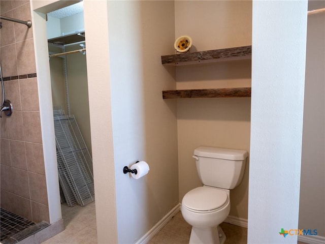 full bathroom featuring toilet, a stall shower, tile patterned flooring, and baseboards