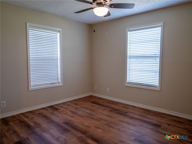 empty room with baseboards, a textured ceiling, and wood finished floors