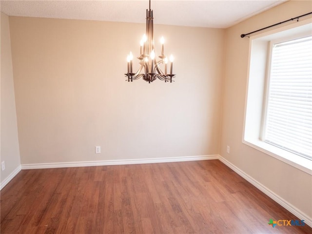 empty room featuring a wealth of natural light, baseboards, and wood finished floors