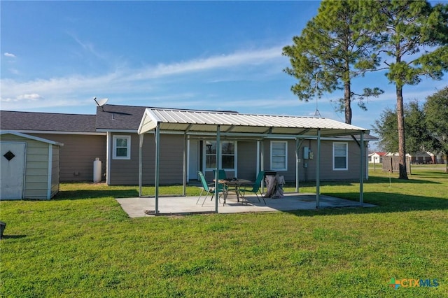 back of house featuring an outbuilding, metal roof, a yard, a shed, and a patio area