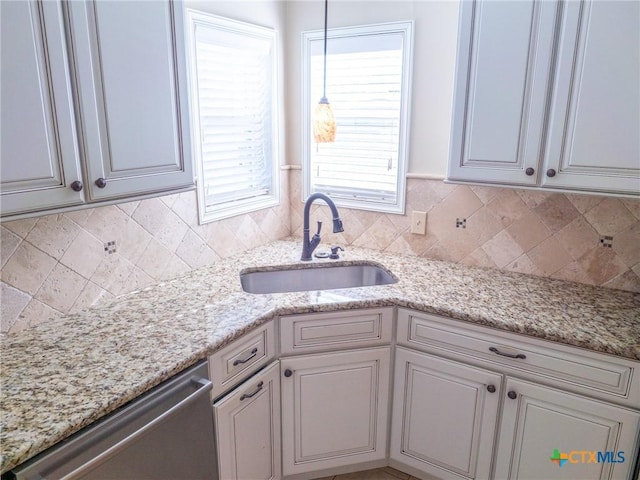 kitchen featuring dishwasher, tasteful backsplash, a sink, and light stone counters