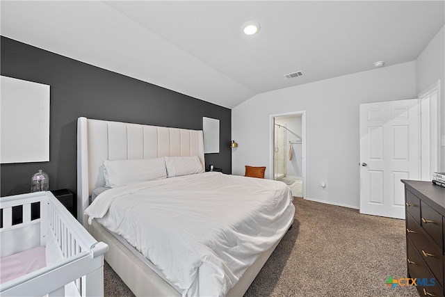 bedroom with ensuite bathroom, dark colored carpet, and vaulted ceiling