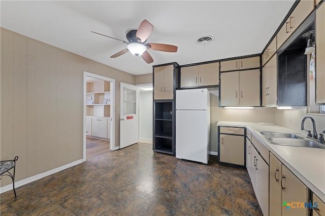 kitchen featuring gray cabinetry, a sink, a ceiling fan, light countertops, and freestanding refrigerator