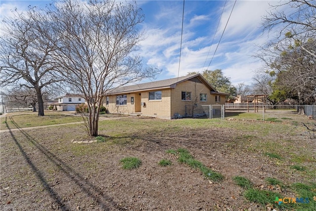 view of property exterior with a yard, brick siding, fence, and a gate