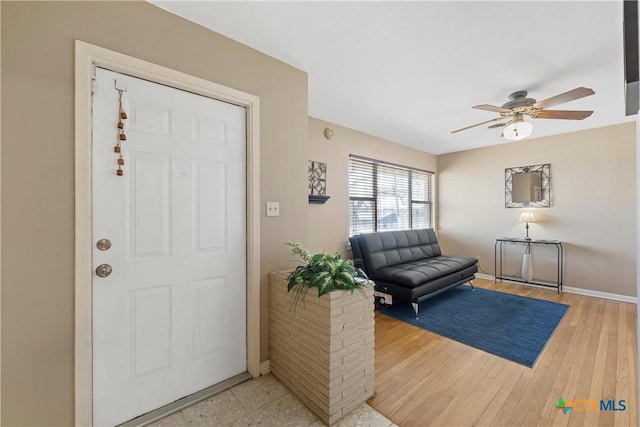 foyer entrance featuring a ceiling fan, light wood-style flooring, and baseboards