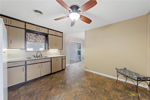 kitchen featuring light countertops, visible vents, stone finish floor, a sink, and baseboards