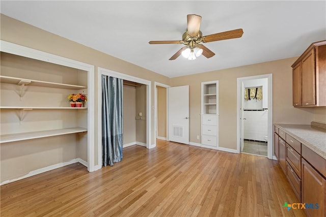 interior space with light wood finished floors, baseboards, visible vents, built in features, and ceiling fan