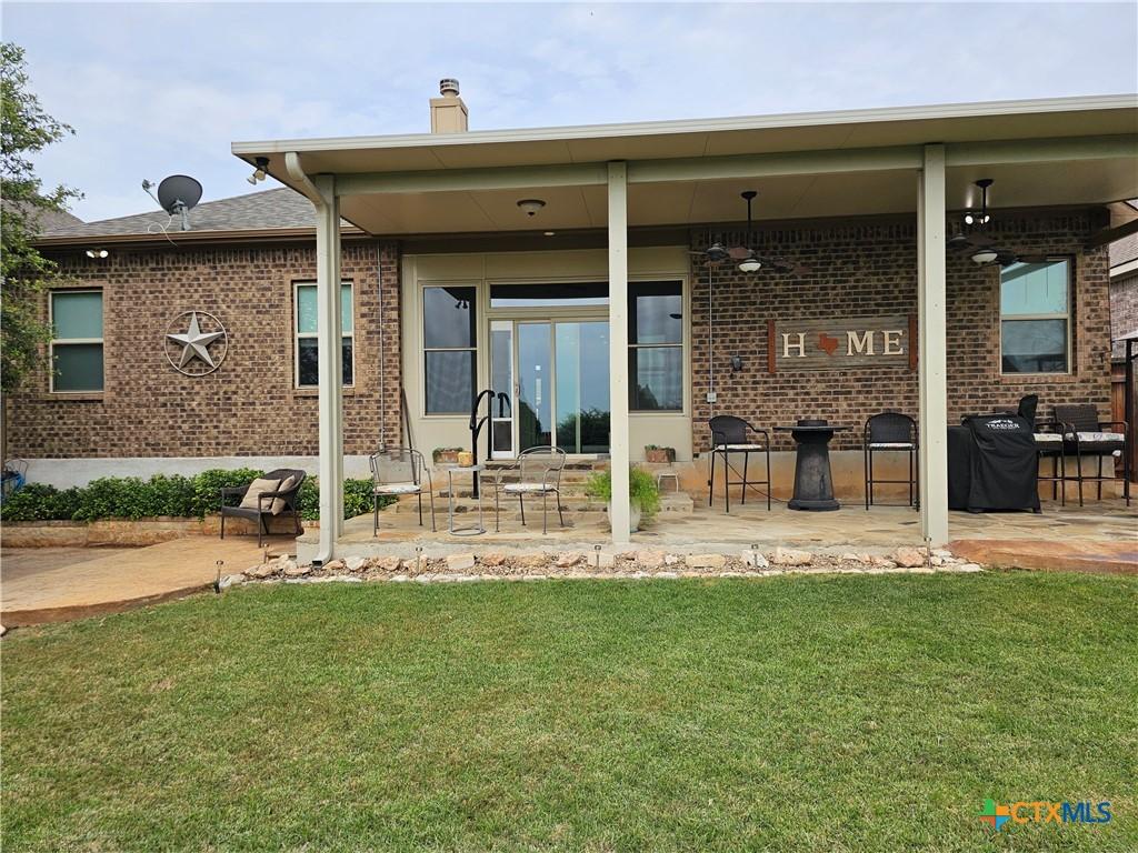 1169 Creek Cyn, New Braunfels, TX 78132 - rear view of house with brick siding, a yard, a patio, and a chimney