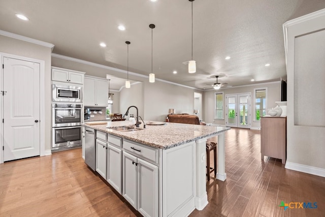 1169 Creek Cyn, New Braunfels, TX 78132 - kitchen with a sink, appliances with stainless steel finishes, open floor plan, recessed lighting, and light wood-style floors
