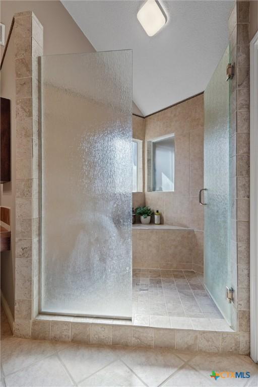 full bathroom featuring a stall shower, lofted ceiling, and tile patterned floors