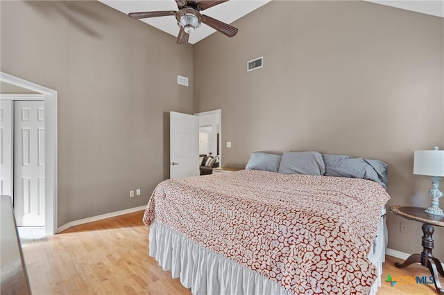 bedroom with high vaulted ceiling, light wood-type flooring, baseboards, and ceiling fan