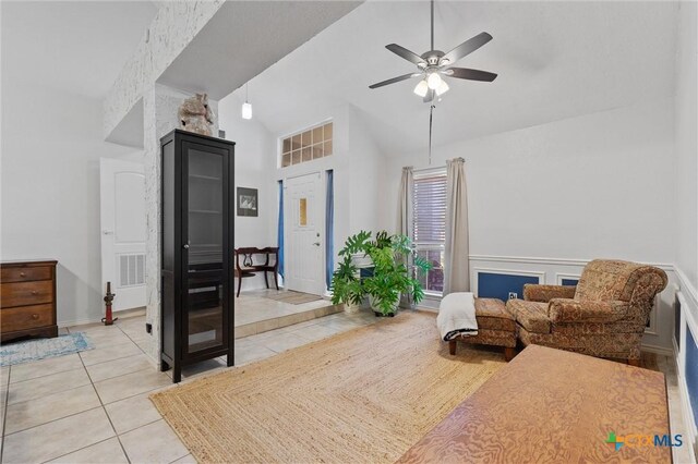 sitting room with high vaulted ceiling, light tile patterned flooring, ceiling fan, and a wainscoted wall