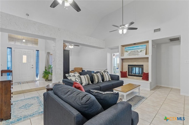 living area with a ceiling fan, light tile patterned flooring, a tiled fireplace, and lofted ceiling