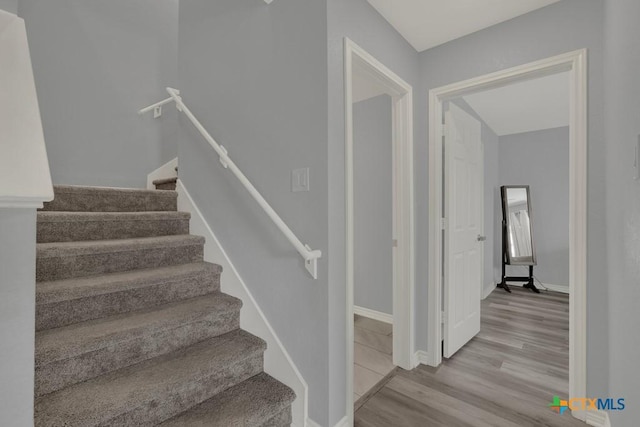 staircase featuring baseboards and wood finished floors