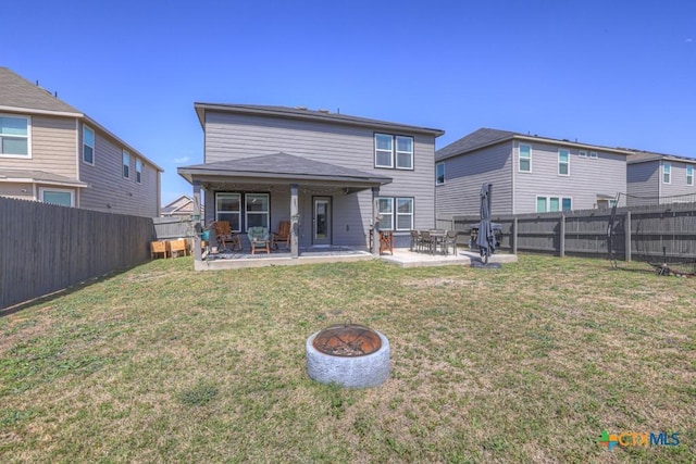 rear view of property featuring a yard, a patio, and a fenced backyard