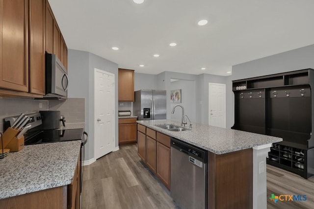 kitchen with light wood finished floors, decorative backsplash, stainless steel appliances, and a sink