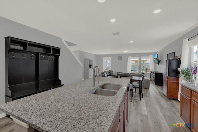 kitchen with light wood-type flooring, brown cabinets, visible vents, a sink, and open floor plan