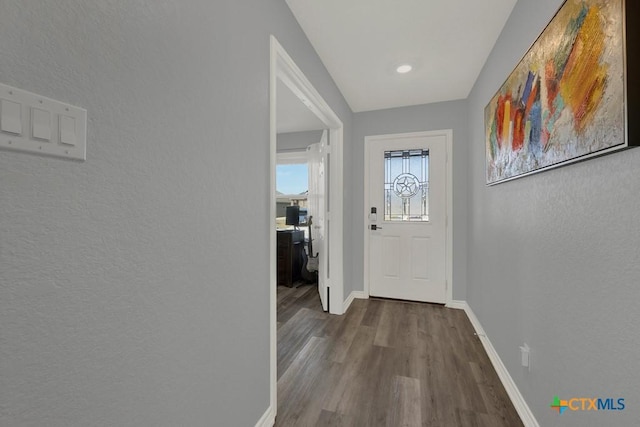 entryway featuring baseboards, wood finished floors, and a textured wall