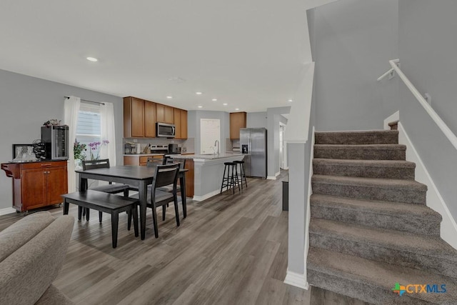 dining area featuring light wood finished floors, recessed lighting, stairs, and baseboards