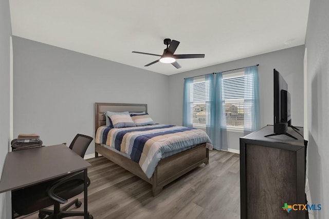 bedroom with a ceiling fan, wood finished floors, and baseboards