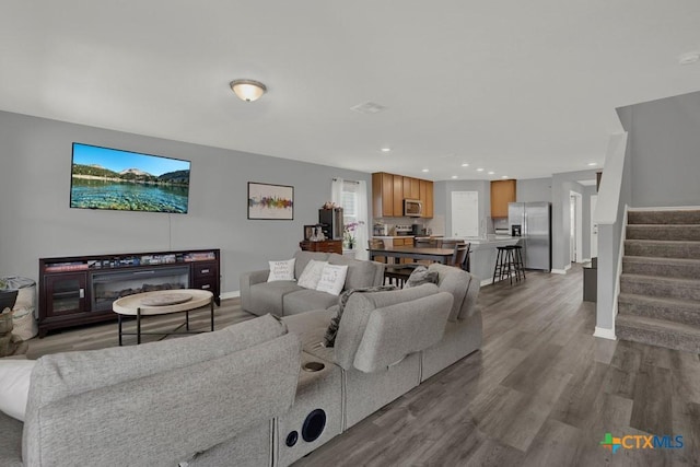 living room featuring stairs, recessed lighting, wood finished floors, and baseboards