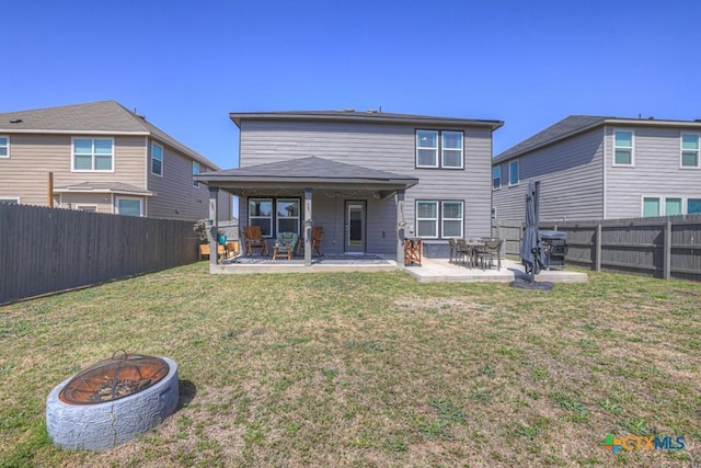 rear view of property with a patio area, a lawn, a fenced backyard, and an outdoor fire pit