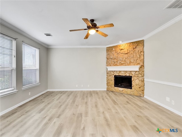 unfurnished living room featuring light hardwood / wood-style floors, a stone fireplace, ceiling fan, and crown molding