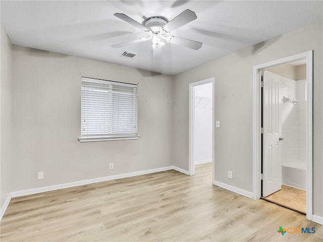 unfurnished bedroom featuring ensuite bath, ceiling fan, a spacious closet, light hardwood / wood-style floors, and a closet