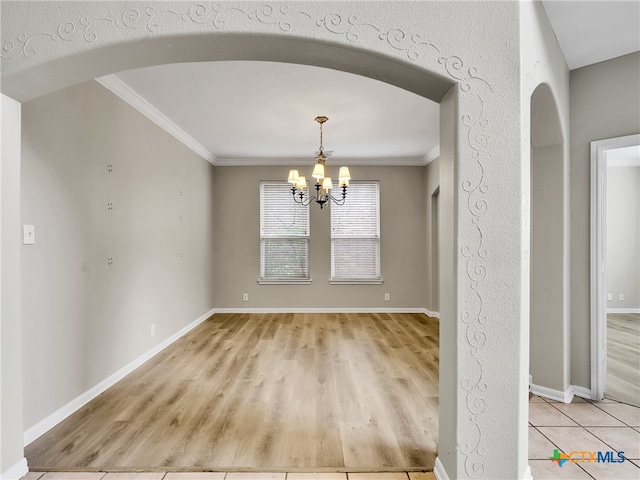 unfurnished dining area with crown molding, a chandelier, and light wood-type flooring