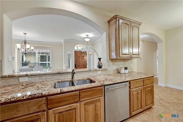 kitchen featuring light stone countertops, tasteful backsplash, stainless steel dishwasher, sink, and an inviting chandelier