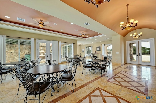 dining room with french doors, ceiling fan with notable chandelier, and a raised ceiling