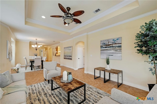 tiled living room featuring a raised ceiling, crown molding, and ceiling fan with notable chandelier