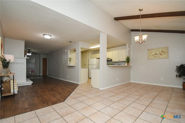 interior space featuring ceiling fan with notable chandelier, lofted ceiling with beams, and a textured ceiling